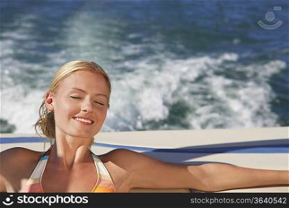 Young woman with eyes closed relaxing on boat smiling