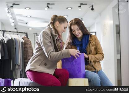 Young woman with friend looking into shopping bag at store
