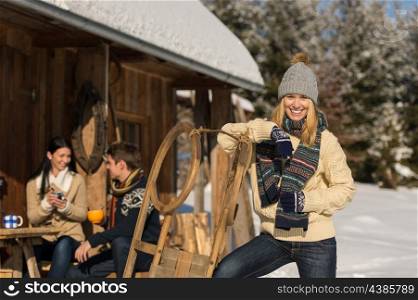 Young woman with friends spending holiday in winter snow cottage