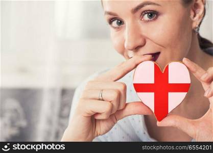 Young woman with gingerbread heart cookies with flag of England. Young woman with gingerbread heart cookies with flag. Young woman with gingerbread heart cookies with flag