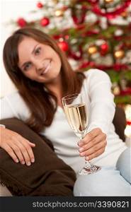 Young woman with glass of champagne in front of Christmas tree
