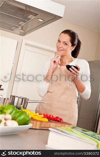 Young woman with glass of red wine in the kitchen