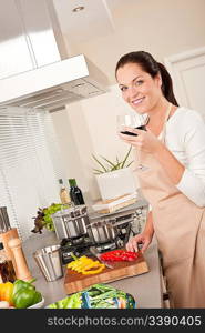 Young woman with glass of red wine in the kitchen