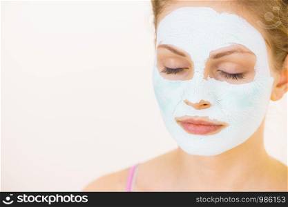 Young woman with green mud mask on face, on white. Teen girl taking care of oily skin, purifying the pores. Beauty treatment. Skincare.. Girl with green mud mask on face