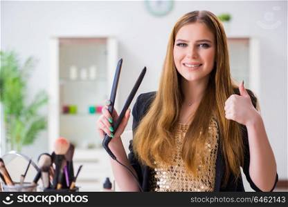 Young woman with hair straightener at home