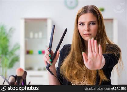 Young woman with hair straightener at home