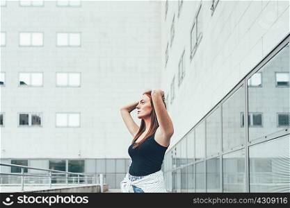 Young woman with hands on head outside office building