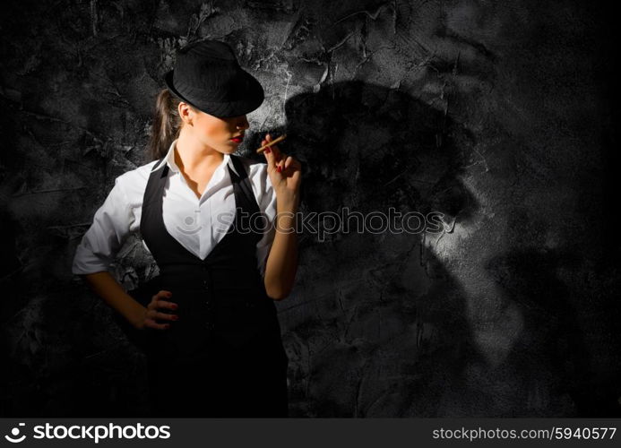 Young woman with hat and cigar on grey wall