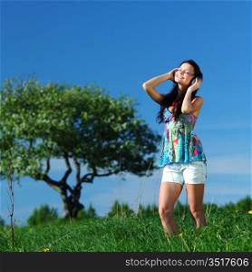 Young woman with headphones listening to music on field