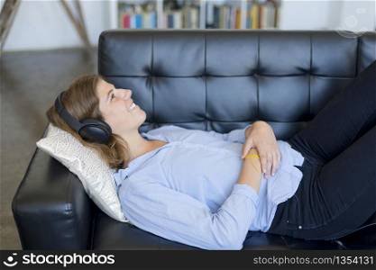 Young woman with headphones relaxing on a sofa