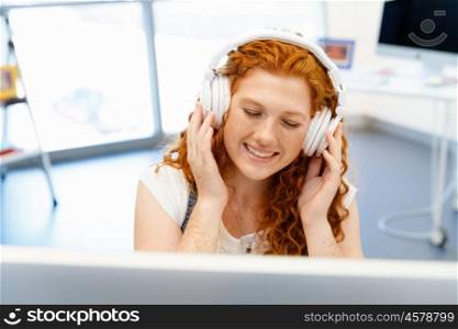 Young woman with headphones working in office. Young woman with headphones working in office at her desk