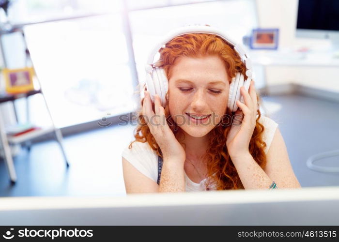 Young woman with headphones working in office. Young woman with headphones working in office at her desk