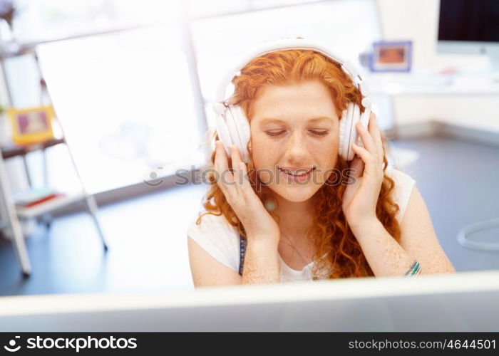 Young woman with headphones working in office. Young woman with headphones working in office at her desk