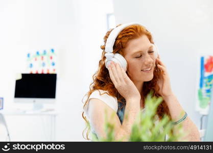 Young woman with headphones working in office. Young woman with headphones working in office at her desk