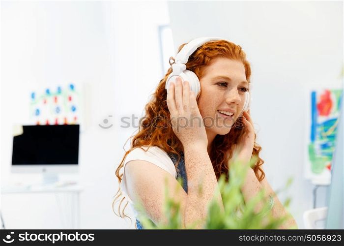 Young woman with headphones working in office. Young woman with headphones working in office at her desk