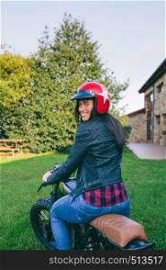 Young woman with helmet riding a custom motorbike outdoors. Woman with helmet riding custom motorbike