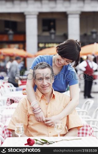 Young woman with her arm around a mature man at a sidewalk cafe