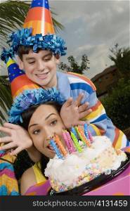 Young woman with her brother in front of a birthday cake