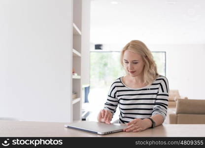 Young woman with her laptop computer in her luxury modern home, smiling