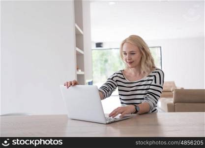 Young woman with her laptop computer in her luxury modern home, smiling