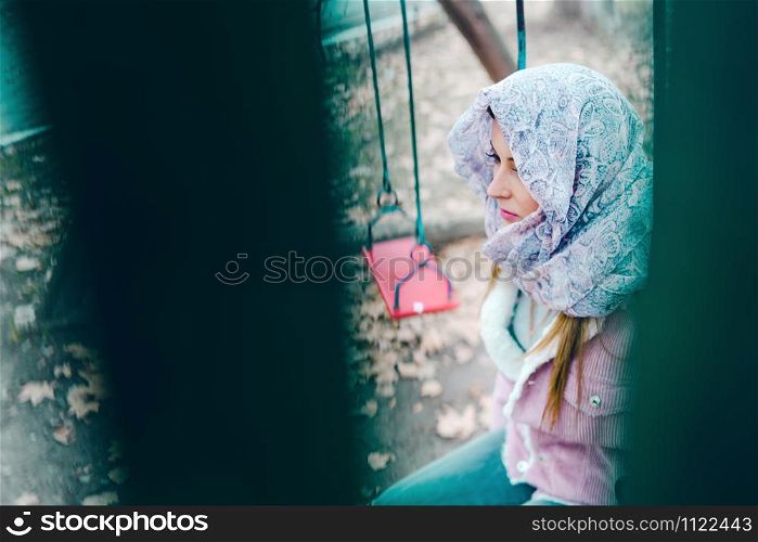 Young woman with hijab over head on Swing