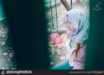 Young woman with hijab over head on Swing