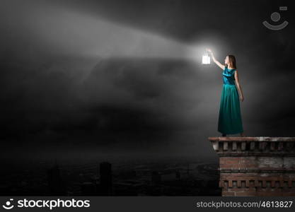 Young woman with lantern walking in darkness. Lost in darkness