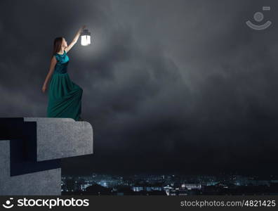 Young woman with lantern walking in darkness. Lost in darkness