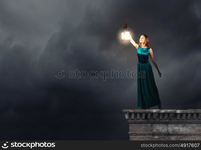 Young woman with lantern walking in darkness. Lost in darkness