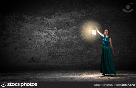 Young woman with lantern walking in darkness. Lost in darkness