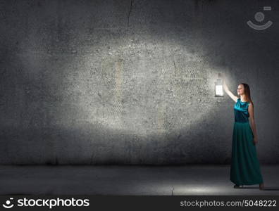 Young woman with lantern walking in darkness. Lost in darkness