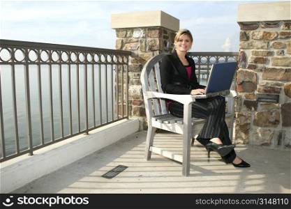 Young woman with laptop by the lake.
