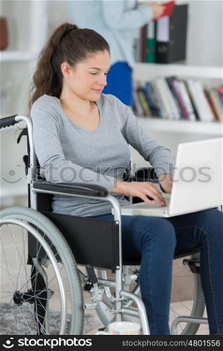 young woman with laptop on the wheelchair