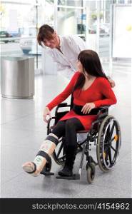young woman with leg in plaster, wheelchair and nurse