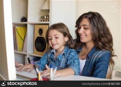 Young woman with little girl using computer at home