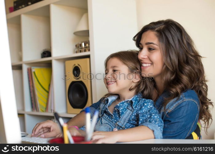 Young woman with little girl using computer at home