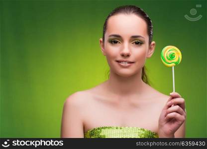 Young woman with lollipop on green background
