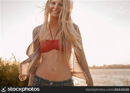 Young woman with long blond hair smiling joyfully on summer beach soft retro colors backlit shot. Young woman with long blond hair smiling joyfully on summer beach soft retro colors backlit photo shot.