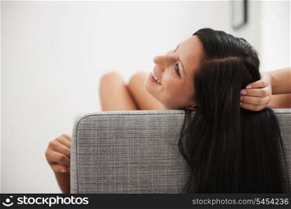 Young woman with long hair laying on couch in living room