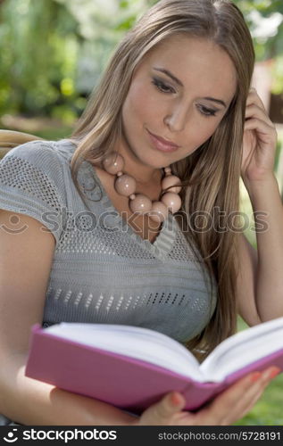 Young woman with long hair reading book in park