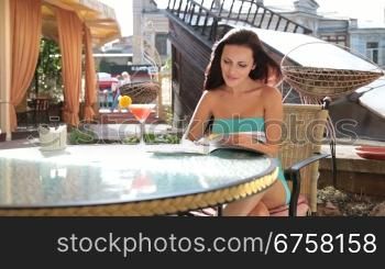 young woman with magazine resting in downtown cafe