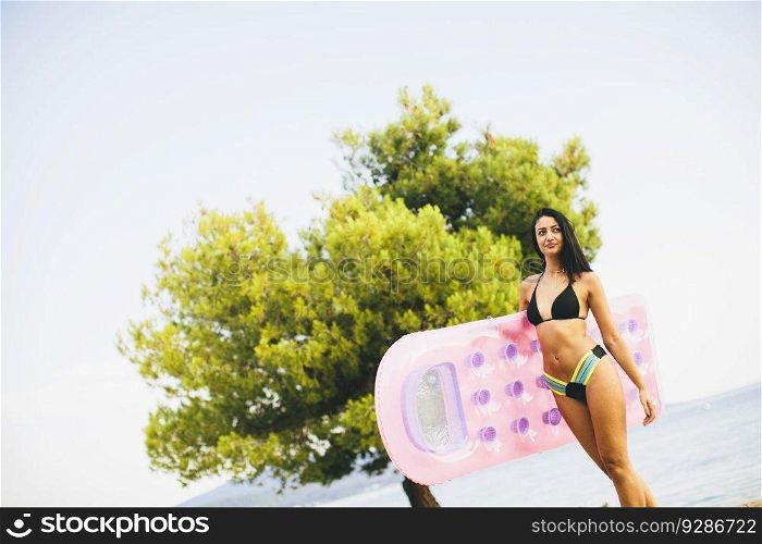Young woman with mettress on the beach at sunny day
