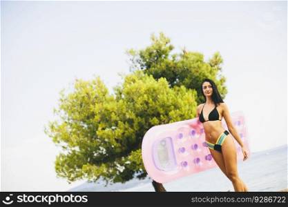 Young woman with mettress on the beach at sunny day
