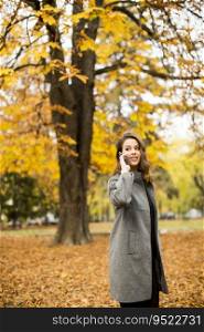 Young woman with mobile phone in the autumn park
