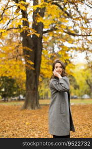 Young woman with mobile phone in the autumn park