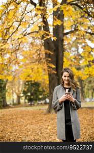 Young woman with mobile phone in the autumn park