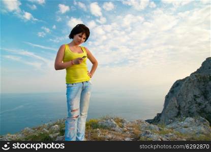 Young woman with mobile phone on cloudscape background