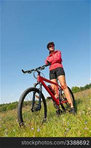 Young woman with mountain bike in spring nature on sunny day