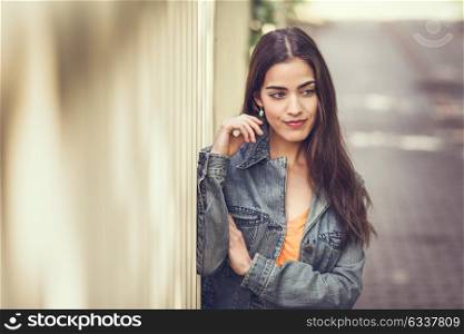 Young woman with nice hair wearing casual clothes in urban background. Happy girl with wavy hairstyle.