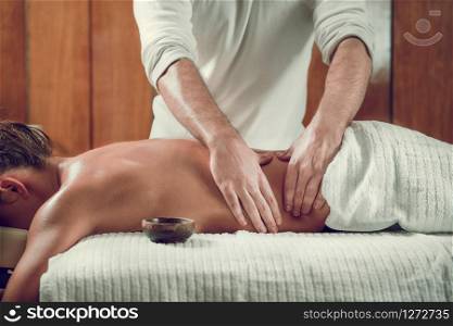 Young woman with oiled skin having relaxing back massage